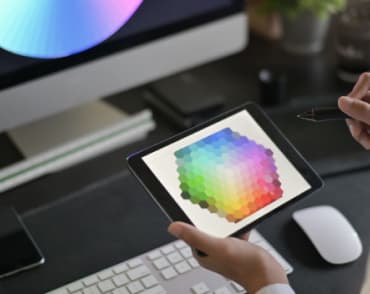 Девушка работает на планшете, на заднем фоне персональный компьютер